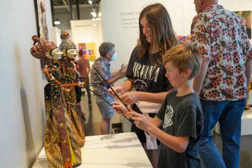 Two youth play with Indonesian marionettes