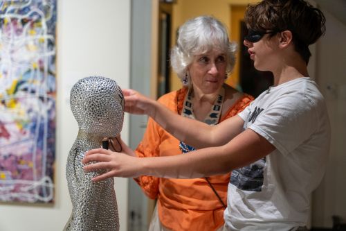A blndfolded guest touches a sequined statue