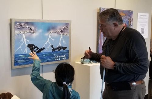 Photo of John Halliday and a gallery visitor examining his work